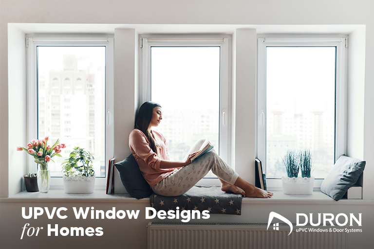 Woman reading by modern uPVC windows at home – Duron window designs.